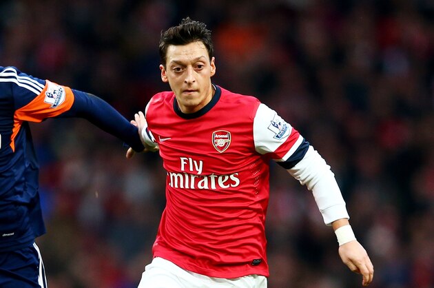 LONDON, ENGLAND - JANUARY 18:  Mesut Oezil of Arsenal holds off Clint Dempsey of Fulham during the Barclays Premier League match between Arsenal and Fulham at Emirates Stadium on January 18, 2014 in London, England.  (Photo by Clive Mason/Getty Images)