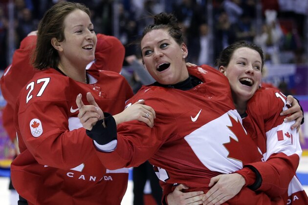 Canada's Tara Watchorn (27), Natalie Spooner (24) and Catherine Ward (18) celebrate after beating the USA 3-2 in overtime of the gold medal women's ice hockey game at the 2014 Winter Olympics, Wednesday, Feb. 19, 2014, in Sochi, Russia. (AP Photo/David Goldman)