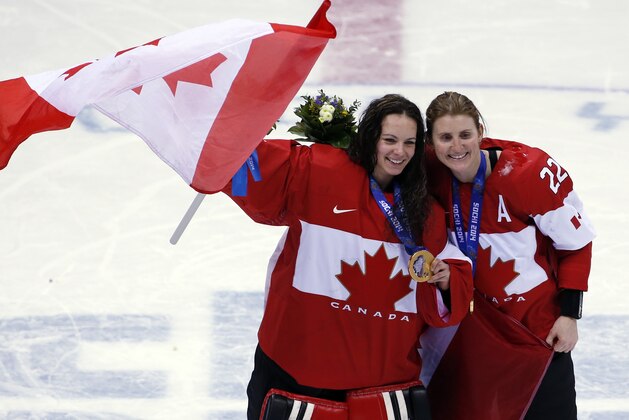 Goalkeeper Shannon Szabados of Canada (1) and Hayley Wickenheiser of Canada (22) celebrate after the medal ceremony in the women's ice hockey tournament at the 2014 Winter Olympics, Friday, Feb. 21, 2014, in Sochi, Russia. Canada won gold after defeated Team USA 3-2 in overtime. (AP Photo/Petr David Josek)