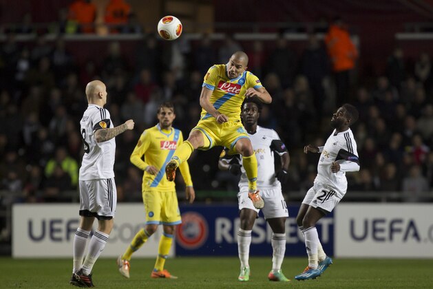 Napoli's Gokhan Inler, center, jumps for the ball as Swansea players including Jonjo Shelvey, left, and Kyle Bartley, right, look on, during their Europa League round of 32 first leg soccer match at the Liberty Stadium, Swansea, Wales, Thursday Feb. 20, 2014. (AP Photo/Jon Super)