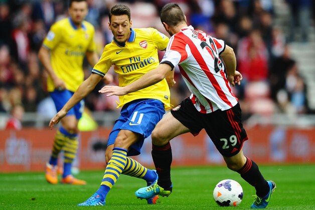 SUNDERLAND, ENGLAND - SEPTEMBER 14:  Mesut Oezil of Arsenal takes on Valentin Roberge of Sunderland during the Barclays Premier League match between Sunderland and Arsenal at the Stadium of Light on September 14, 2013 in Sunderland, England.  (Photo by Laurence Griffiths/Getty Images)