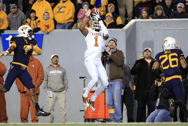 Texas' Mike Davis (1) makes a catch between West Virginia's Daryl Worley (7) and Travis Bell (26) during the fourth quarter of their NCAA college football game in Morgantown, W.Va., on Saturday, Nov.9, 2013. Texas won 47-40 in overtime. (AP Photo/Christopher Jackson)