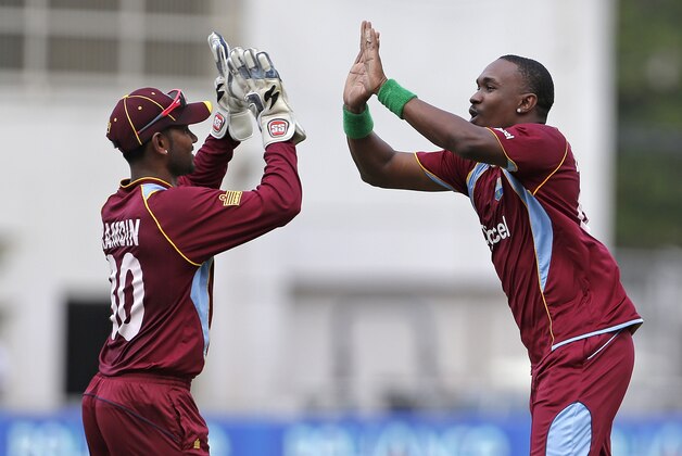 West Indies' Dwayne Bravo, right, highs five with his wicket keeper Denesh Ramdin after they took the wicket of Sri Lanka's opener Upul Tharanga, who was caught behind for 25 runs, during their Tri-Nation Series cricket match in Kingston, Jamaica, Friday, June 28, 2013. (AP Photo/Andres Leighton)