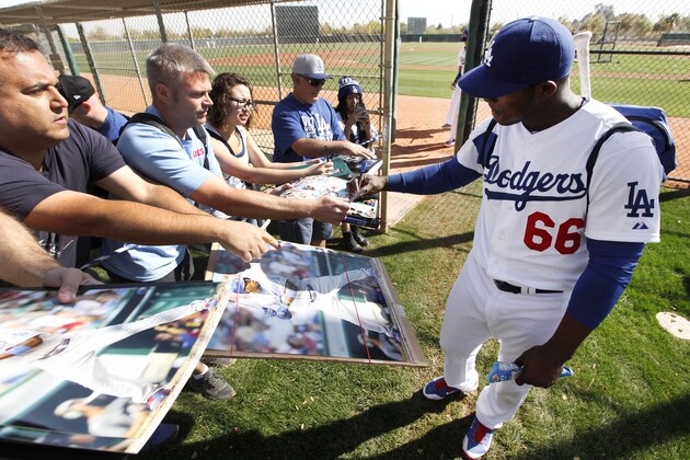 Los Angeles Dodgers' Yasiel Puig signs autographs for fans after spring training baseball practice in Glendale, Ariz., Friday, Feb. 14, 2014. (AP Photo/Paul Sancya)
