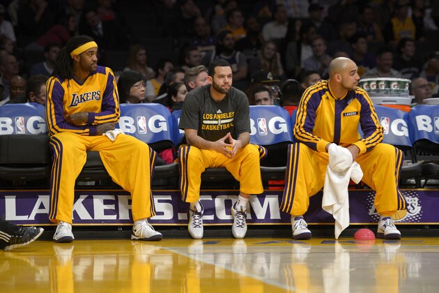 Los Angeles Lakers forward Jordan Hill, left, guard Jordan Farmar, center, and center Robert Sacre watch from the bench during the first half of an NBA basketball game against the Houston Rockets, Wednesday, Feb. 19, 2014, in Los Angeles. (AP Photo/Mark J. Terrill)