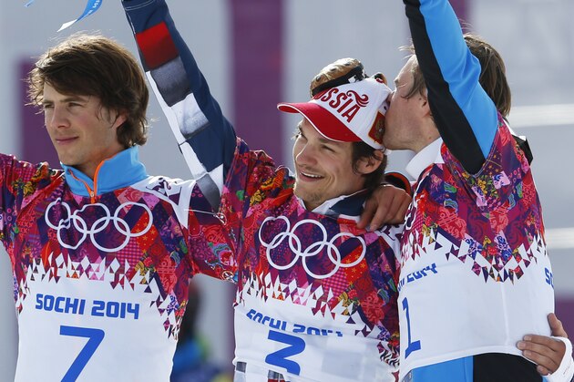 Men's snowboard parallel slalom gold medalist Vic Wild of Russia, center, is kissed by bronze medalist Benjamin Karl, right, as silver medalist Zan Kosir of Slovenia, left, celebrates, at the Rosa Khutor Extreme Park, at the 2014 Winter Olympics, Saturday, Feb. 22, 2014, in Krasnaya Polyana, Russia.(AP Photo/Sergei Grits)