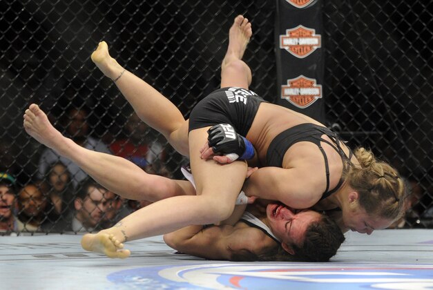Ronda Rousey, of Venice, Calif., and Miesha Tate, of Yakima, Wash., battle it out during the UFC 168 mixed martial arts women's bantamweight title fight on Saturday, Dec. 28, 2013, in Las Vegas. Rousey won by a third round tap out. (AP Photo/David Becker)