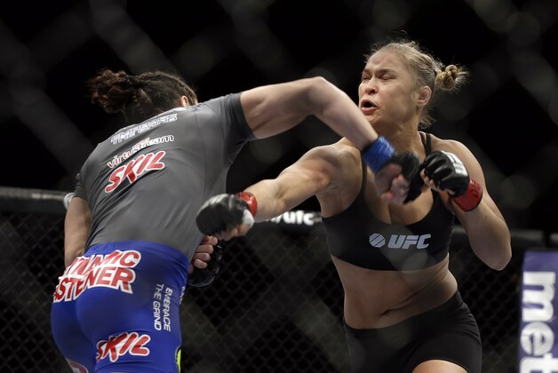 Ronda Rousey, right, and Sara McMann exchange punches during a UFC 170 mixed martial arts women's bantamweight title fight on Saturday, Feb. 22, 2014, in Las Vegas. (AP Photo/Isaac Brekken)