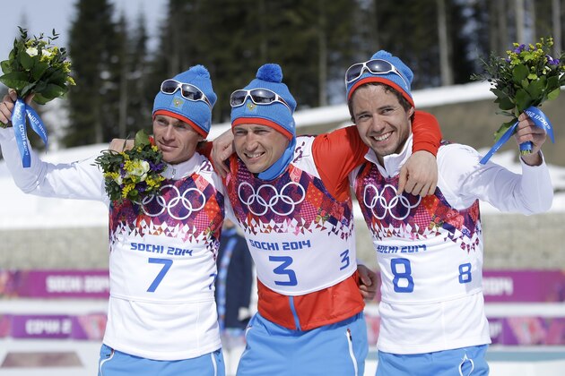 Russia's gold medal winner Alexander Legkov is flanked by Russia's silver medal winner Maxim Vylegzhanin, left and Russia's bronze medal winner Ilia Chernousov during the flower ceremony of the men's 50K cross-country race at the 2014 Winter Olympics, Sunday, Feb. 23, 2014, in Krasnaya Polyana, Russia. (AP Photo/Gregorio Borgia)