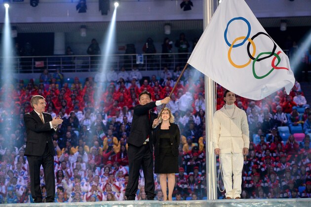 International Olympic Committee President Thomas Bach, left, applauds as Lee Seok-rai, mayor of Pyeongchang, waves the Olympic flag during the closing ceremony of the 2014 Winter Olympics, Sunday, Feb. 23, 2014, in Sochi, Russia. (AP Photo/Jung Yeon-je, Pool)