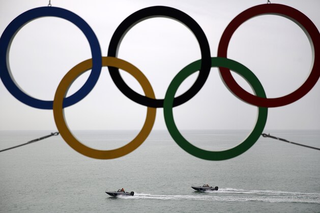 Russian Coast Guard vessels patrol the Black Sea past the Olympic rings hanging outside a train station near the 2014 Winter Olympics, Saturday, Feb. 22, 2014, in Adler, Russia. (AP Photo/David Goldman)