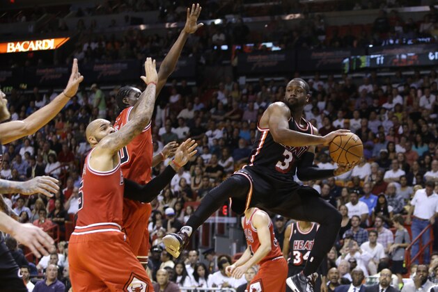 Miami Heat's Dwyane Wade (3) looks to pass as Chicago Bulls' Tony Snell, center, and Carlos Boozer (5) defend during the first half of an NBA basketball game, Sunday, Feb. 23, 2014, in Miami. (AP Photo/Lynne Sladky)