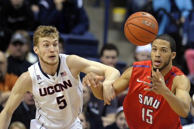 Connecticut's Niels Giffey (5) and SMU's Cannen Cunningham (15) fight for the loose ball during the first half of an NCAA college basketball game in Storrs, Conn., Sunday, Feb. 23, 2014. (AP Photo/Fred Beckham)