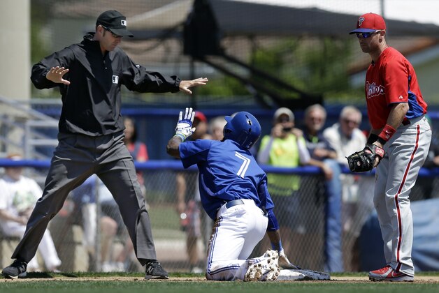 Philadelphia Phillies third baseman Michael Young, right, watches as Toronto Blue Jays Jose Reyes (7) checks with third base umpire Travis Carlson after sliding into third on two-run triple in the second inning of a spring training baseball game in Dunedin, Fla., Monday, March 25, 2013.  The Blue Jays had an eight-run second inning in their 13-4 victory. (AP Photo/Kathy Willens)