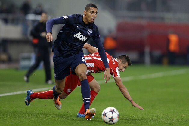 Olympiakos Hernan Perez, right, falls as Manchester United's Chris Smalling controls the ball during their Champions League, round of 16, first leg soccer match at Georgios Karaiskakis stadium, in Piraeus port, near Athens, on Tuesday, Feb. 25, 2014. (AP Photo/Thanassis Stavrakis)