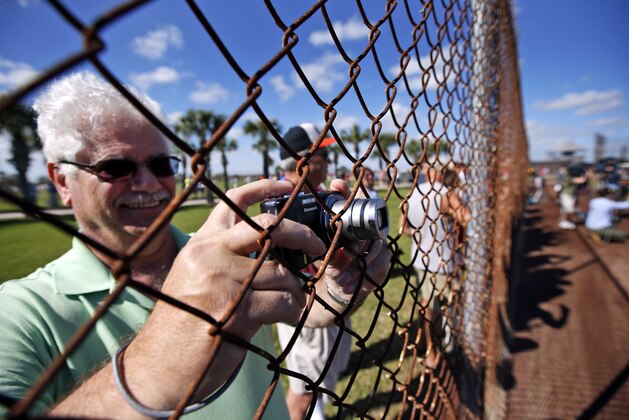 A fan pokes his camera through the fence during a Washington Nationals spring training baseball workout, Thursday, Feb. 20, 2014, in VIera, Fla. (AP Photo/Alex Brandon)