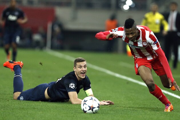 Olympiakos' Michael Olaitan right, goes for the ball as Manchester United's captain Nemanja Vidic looks on  during their Champions League, round of 16, first leg soccer match at Georgios Karaiskakis stadium, in Piraeus port, near Athens, on Tuesday, Feb. 25, 2014. (AP Photo/Petros Giannakouris)