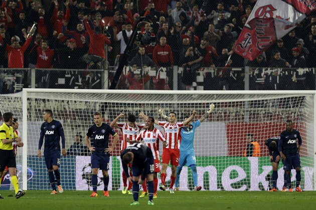 Olympiakos' and Manchester United's players react after Italian's referee Gianluca Rocchi, left, blew the final whistle during a Champions League, round of 16, first leg soccer match against Olympiakos at Georgios Karaiskakis stadium, in Piraeus port, near Athens, on Tuesday, Feb. 25, 2014. Olympiakos won 2-0. (AP Photo/Thanassis Stavrakis)