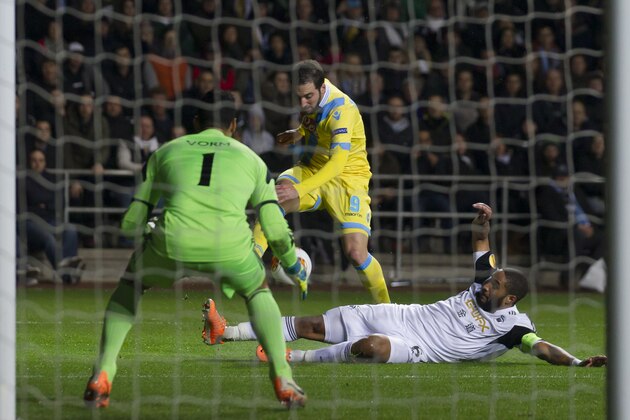 Napoli's Gonzalo Higuain, centre, has a shot blocked by Swansea's Ashley Williams, right, as goalkeeper Michel Vorm looks on during their Europa League round of 32 first leg soccer match at the Liberty Stadium, Swansea, Wales, Thursday, Feb. 20, 2014. (AP Photo/Jon Super)
