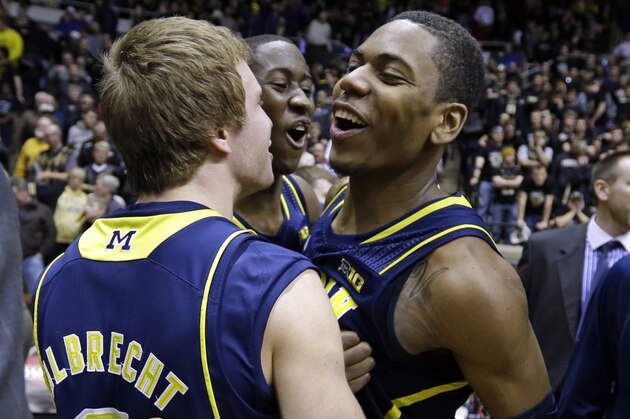 Michigan forward Glenn Robinson III, right, is hugged by teammates Spike Albrecht, left, and Caris LeVert after hitting a game-winning shot as time expired in overtime against Purdue in an NCAA college basketball game in West Lafayette, Ind., Wednesday, Feb. 26, 2014. Michigan defeated Purdue 77-76. (AP Photo/Michael Conroy)