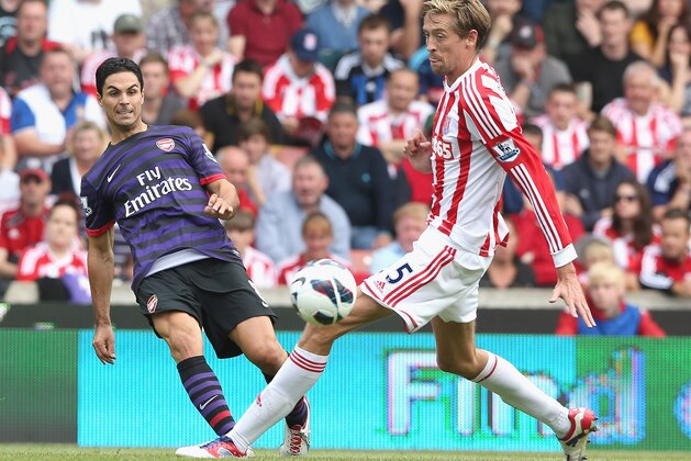 STOKE ON TRENT, ENGLAND - AUGUST 26:  Mikel Arteta of Arsenal passes the ball past Peter Crouch during the Barclays Premier League match between Stoke City and Arsenal at the Britannia Stadium on August 26, 2012 in Stoke on Trent, England.  (Photo by David Rogers/Getty Images)