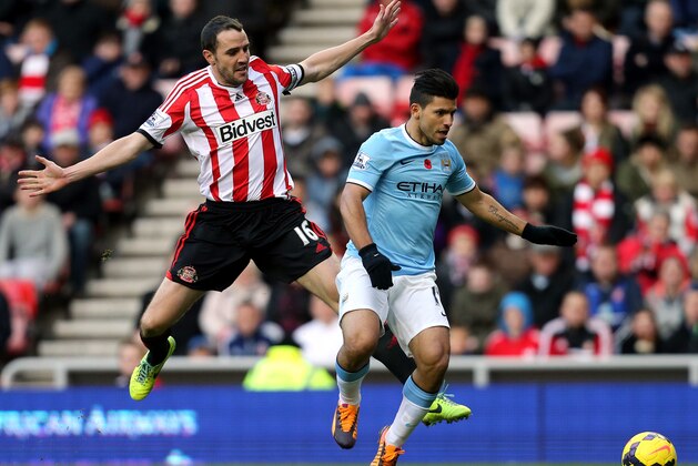 Manchester City's Sergio Aguero, right, vies for the ball with Sunderland's captain John O'Shea, left, during their English Premier League soccer match at the Stadium of Light, Sunderland, England, Sunday, Nov. 11, 2013. (AP Photo/Scott Heppell)
