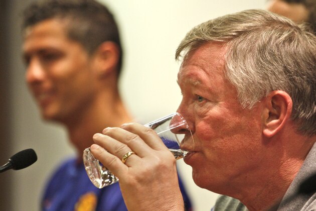 Manchester United coach Alex Ferguson has a drink as Cristiano Ronaldo is seen in background,during a news conference ahead of Wednesday's Champions League final match between Manchester United and Barcelona, at the Rome Olympic stadium, Tuesday, May 26, 2009. (AP Photo/Odd Andersen)