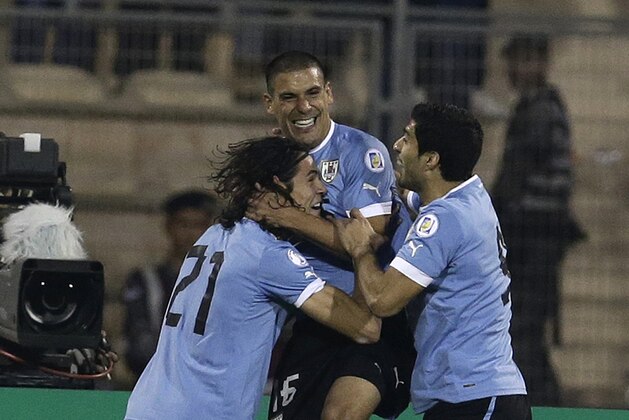 Uruguay's Maximiliano Pereira, right, celebrates with his teammates Edinson Cavani, left, and Luis Suarez after scoring the opening goal against Jordan during the World Cup play off first leg soccer match between Jordan and Uruguay at Amman International stadium in Amman, Jordan, Wednesday, Nov. 13, 2013. (AP Photo/Hassan Ammar)