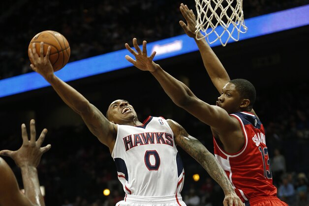 Atlanta Hawks point guard Jeff Teague (0) goes up for a basket as Washington Wizards center Kevin Seraphin (13) defends in the first half of an NBA basketball basketball game  Wednesday, Feb. 19, 2014, in Atlanta.   (AP Photo/John Bazemore)