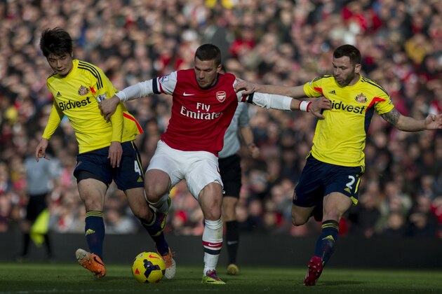 Arsenal's Lukas Podolski, fights for the ball with Sunderland's Ki Sung-Yong (left) and Phillip Bardsley, during their English Premier League soccer match, at Emirates Stadium, in London, Saturday, Feb. 22, 2014. (AP Photo/Bogdan Maran)