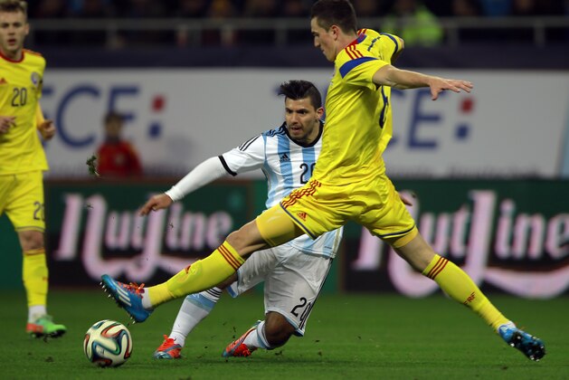 Argentina's Sergio Aguero, left, challenges for the ball with Romania's Florin Gardos, left, during an international friendly soccer game on the National Arena stadium in Bucharest, Romania, Wednesday, March 5, 2014. (AP Photo/Vadim Ghirda)