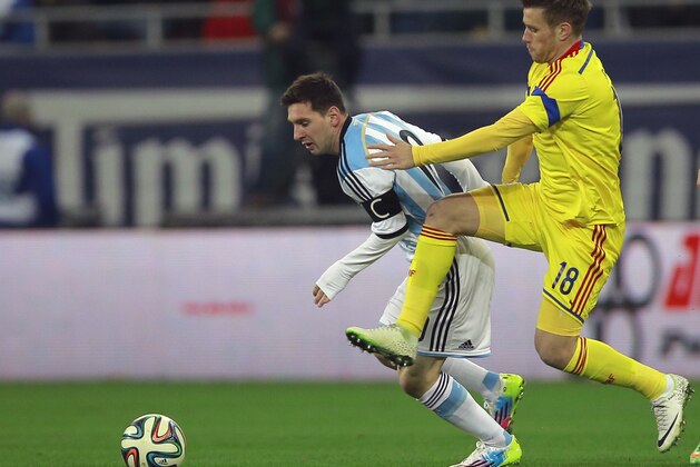 Argentina's Lionel Messi, left, challenges for the ball with Romania's Mihai Pintilii, right, during an international friendly soccer game on the National Arena stadium in Bucharest, Romania, Wednesday, March 5, 2014.. (AP Photo/Vadim Ghirda)