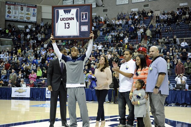 Shabazz Napier, joined by his family on senior day, holds up a plaque before Connecticut's NCAA college basketball game against Rutgers in Storrs, Conn., Wednesday, March 5, 2014. (AP Photo/Fred Beckham)