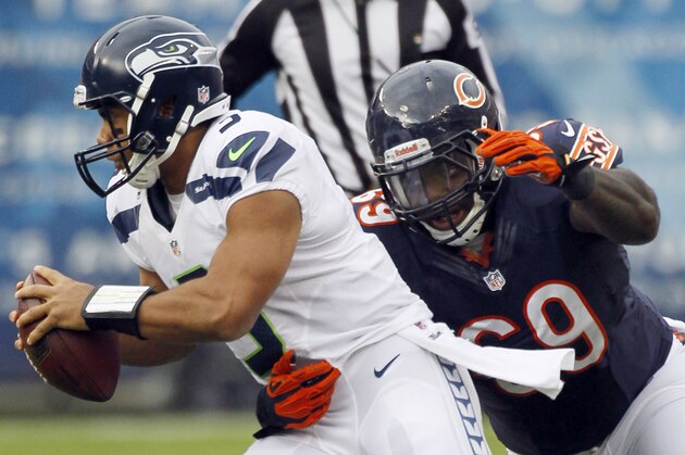 Seattle Seahawks quarterback Russell Wilson (3) scrambles away from Chicago Bears defensive tackle Henry Melton (69) in the first half of an NFL football game in Chicago, Sunday, Dec. 2, 2012. Wilson was able to get a pass off on the play. (AP Photo/Charles Rex Arbogast)