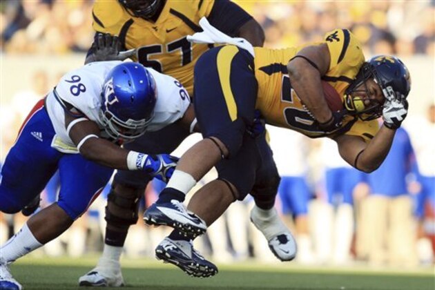 West Virginia running back Shawne Alston (20) is tackled by Kansas' Keon Stowers (98) during the first quarter of their NCAA college football game in Morgantown, W.Va., on Saturday, Dec. 1, 2012. West Virginia won 59-10. (AP Photo/Christopher Jackson)