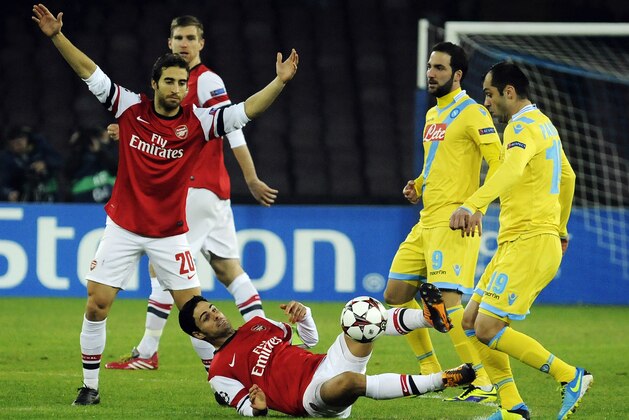 Arsenal's Arteta, center, goes for the ball as teammate Mathieu Flamini, left, Napolis' Goran Pandev, right, and Gonzalo Higuain, second right, wacth him, during a Champions League, group F, soccer match at the Naples San Paolo stadium, Italy, Wednesday, Dec. 11, 2013. (AP Photo/Salvatore Laporta)