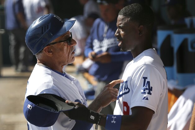 Los Angeles Dodgers coach Davey Lopes, left, talks with second baseman Dee Gordon in the dugout during a spring exhibition baseball game against the Texas Rangers in Glendale, Ariz., Friday, March 7, 2014. (AP Photo/Paul Sancya)