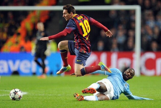 Manchester City's Yaya Toure, right, attempts a tackle Barcelona's Lionel Messi during their Champions League Round of 16 soccer match at the Etihad Stadium in Manchester, England, Tuesday, Feb. 18, 2014. (AP Photo/Clint Hughes)