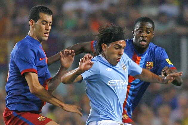 Manchester City's Carlos Tevez, center, fights for the ball with FC Barcelona's Sergio Busquets, left, and Yaya Toure during their Joan Gamper Trophy soccer match at the Camp Nou stadium in Barcelona, Spain, Wednesday, Aug. 19, 2009. (AP Photo/ David Ramos)