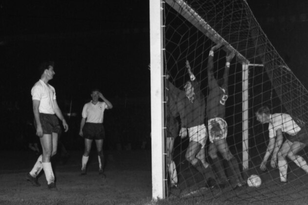 Tottenham full-back Peter Baker, right, picks the ball out of the net after Benfica had scored their second goal in the European Cup semi-final, first leg, in Lisbon, on March 21, 1962. Benfica defeated Tottenham 3-1. (AP Photo)