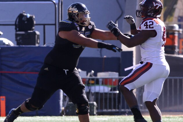 UCLA guard Xavier Su'a-Filo fends off a Virginia Tech defender during the Sun Bowl NCAA college football game on Tuesday Dec. 31, 2013. (AP Photo/Victor Calzada)