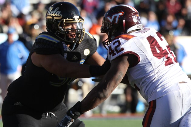 UCLA guard Xavier Su'a-Filo fends off a Virginia Tech defender at the Hyundai Sun Bowl.during the Sun Bowl NCAA college football game on Tuesday Dec. 31, 2013. (AP Photo/Victor Calzada)