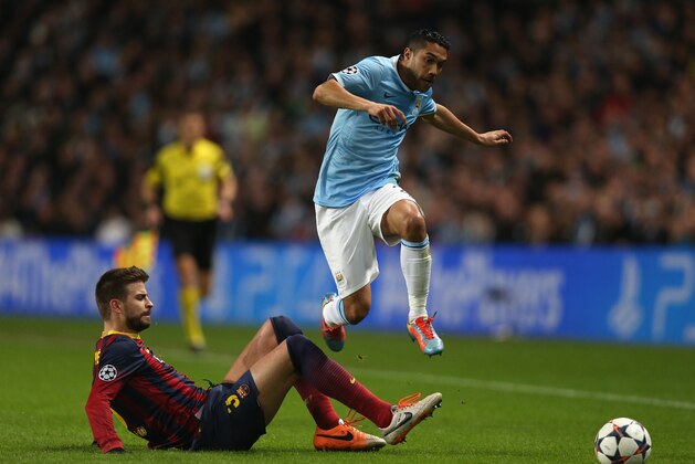 MANCHESTER, ENGLAND - FEBRUARY 18:  Gael Clichy of Manchester City hurdles the tackle of Gerard Pique of Barcelona during the UEFA Champions League Round of 16 first leg match between Manchester City and Barcelona at the Etihad Stadium on February 18, 2014 in Manchester, England.  (Photo by Clive Brunskill/Getty Images)