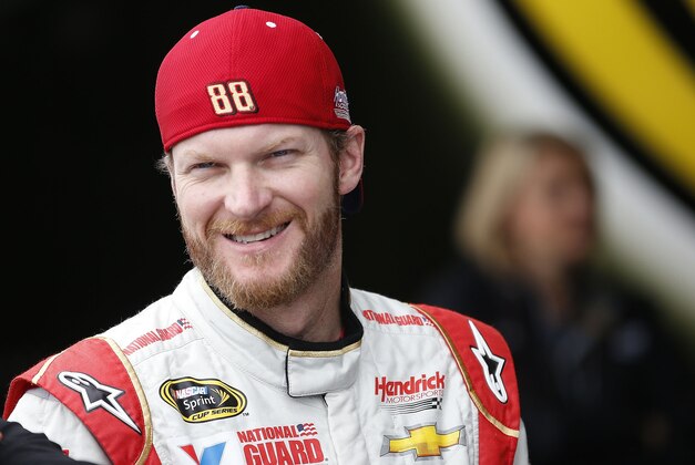 Dale Earnhardt, Jr., smiles as he stands talking with crew members in the garage during NASCAR Sprint Cup auto racing practice Saturday, March 1, 2014, in Avondale, Ariz. (AP Photo/Ross D. Franklin)