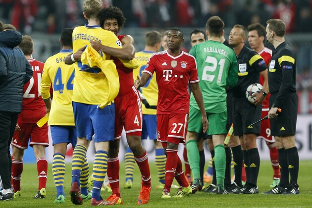 Arsenal's Per Mertesacker, front left, hugs Bayern's Dante after the Champions League round of 16 second leg soccer match between FC Bayern Munich and FC Arsenal in Munich, Germany, Wednesday, March 12, 2014. (AP Photo/Matthias Schrader)