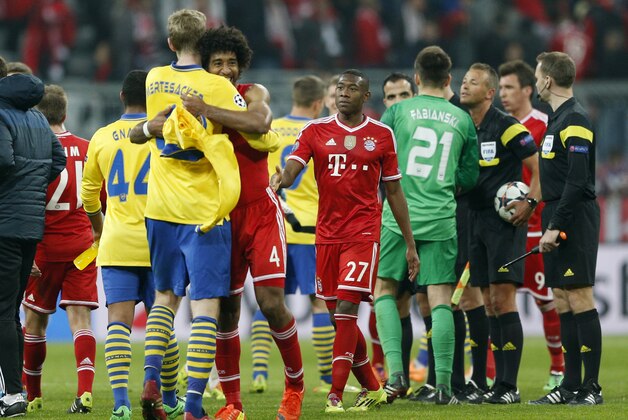Arsenal's Per Mertesacker, front left, hugs Bayern's Dante after the Champions League round of 16 second leg soccer match between FC Bayern Munich and FC Arsenal in Munich, Germany, Wednesday, March 12, 2014. (AP Photo/Matthias Schrader)