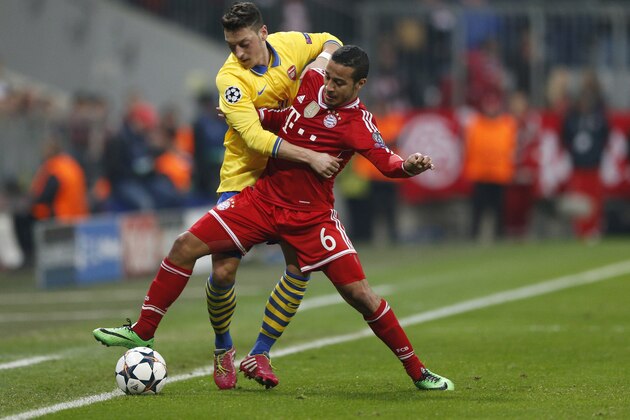 Arsenal's Mesut Ozil, left, and Bayern's Thiago Alcantara challenge for the ball during the Champions League round of 16 second leg soccer match between FC Bayern Munich and FC Arsenal in Munich, Germany, Wednesday, March 12, 2014. (AP Photo/Matthias Schrader)