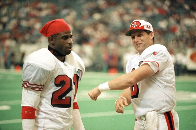 San Francisco 49ers quarterback Steve Young (8) jokes with cornerback Deion Sanders (21) as the 49ers downed the Falcons 42-3 at the Georgia Dome in Atlanta, Sunday, Oct. 16, 1994. (AP Photo/John Bazemore)