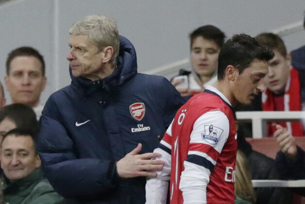 Arsenal's Mesut Ozil, right, is patted by his French manager Arsene Wenger after being substituted off during the English Premier League soccer match between Arsenal and Fulham at the Emirates Stadium in London, Saturday, Jan. 18, 2014.  (AP Photo/Matt Dunham)