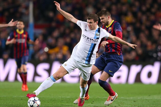 BARCELONA, SPAIN - MARCH 12:  Edin Dzeko of Manchester City is tackled by Gerard Pique of FC Barcelona during the UEFA Champions League Round of 16 match between FC Barcelona and Manchester City at Camp Nou on March 12, 2014 in Barcelona, Spain.  (Photo by Alex Livesey/Getty Images)